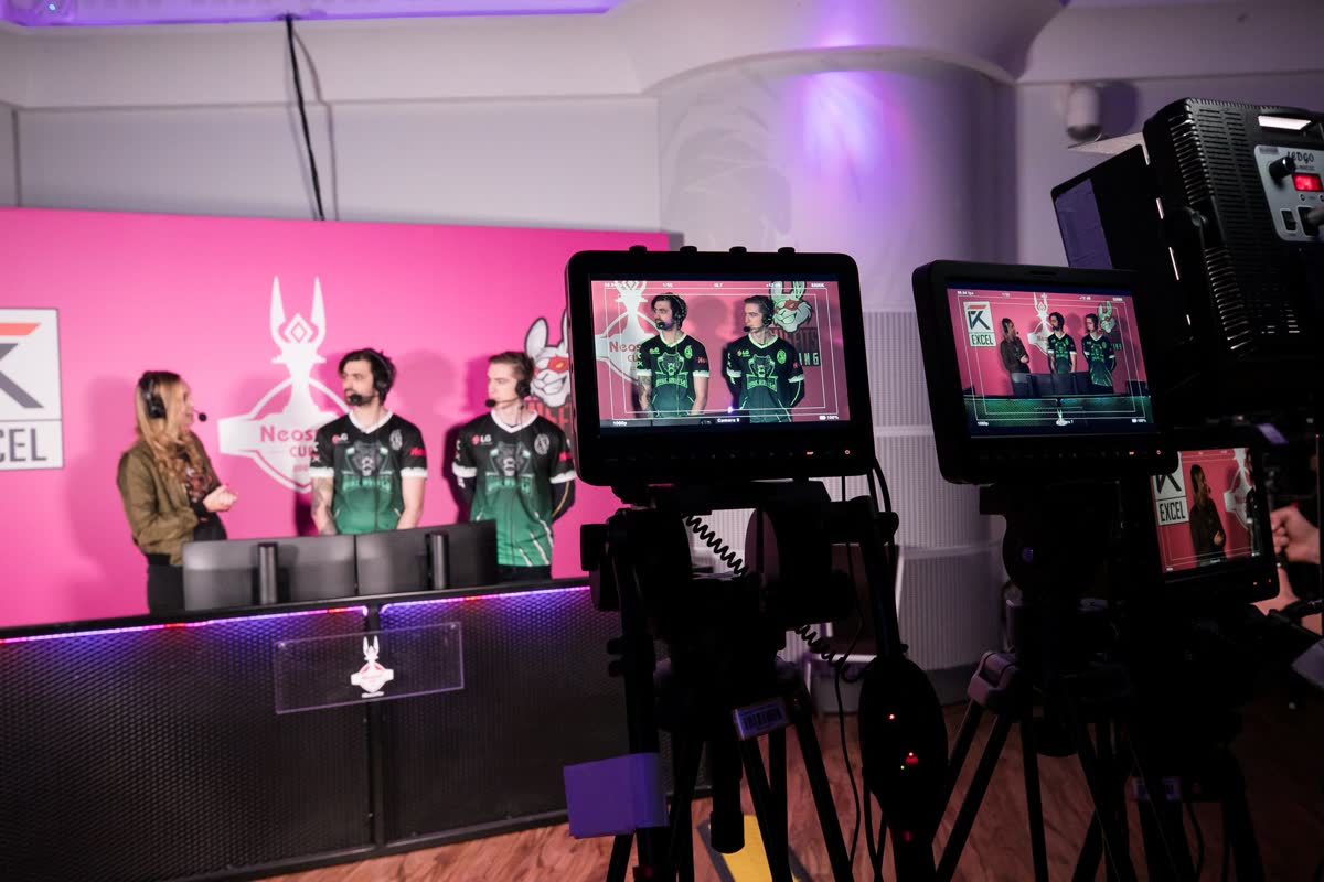 Neosurf Cup 2020 경기장 — 핑크·보라 조명 아래 e스포츠 무대와 관중, 대형 화면의 리그 오브 레전드 경기